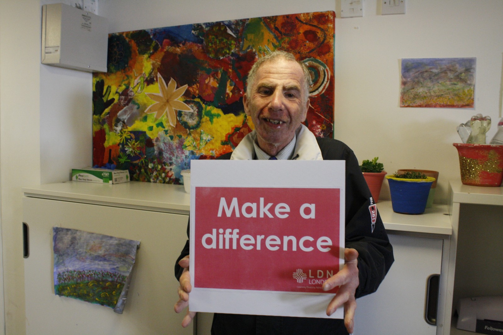 Malcolm at LDN Community Hub holding a sign saying Make a Difference